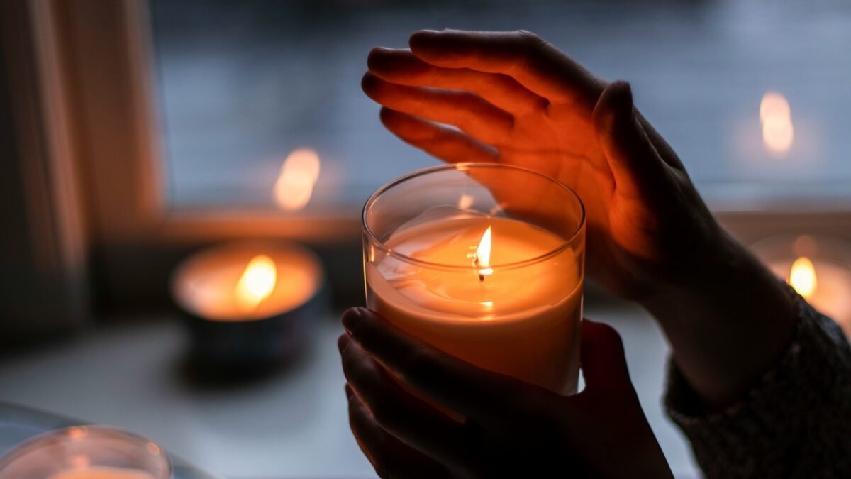 Hands holding lit candles glowing in the dark