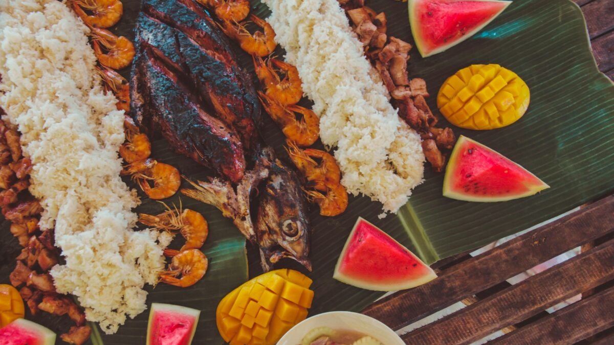 A Filipino boodle fight spread of rice, grilled fish and shrimp laid out for a shared family meal